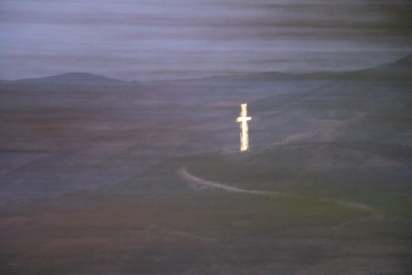a glowing white cross standing in mountains