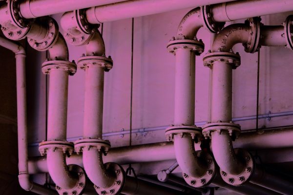 a pink-tinted image of some metal pipes, joined together with bolts
