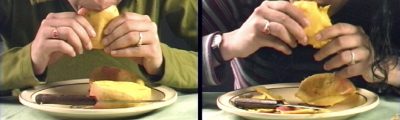 a film still of a man on the left and a woman on the right eating mangoes with their hands, above plates with knives resting on them, as well as cut pieces of mango. 