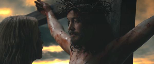 A still from Benedetta, featuring Christ on the cross looking at Benedetta.